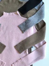Polera fucsia de tejido de punto con cuello alto y mangas largas con botones decorativos en los puños.