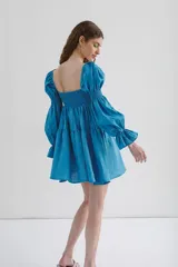 Vestido corto blanco de lino, con escote recto, mangas abullonadas 3/4 con elástico y falda con volado.