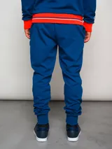 Pantalón de jogging azul con puños ajustados, cintura elástica con cordón y escudo del Club Nacional de Football en la pierna izquierda.