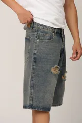 Bermuda de jean azul con efecto lavado y roturas en la parte delantera.