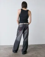 Pantalón de jean gris con recortes y costuras rojas, de tiro medio y pierna ancha, con escorpiones bordados en los bolsillos traseros.