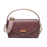 Bandolera de PU color bordó con textura granulada y costuras blancas visibles. Presenta solapa frontal con logo metálico XL y herrajes dorados. Incluye correa larga regulable y desmontable, y asa superior de cuero marrón.