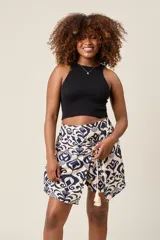 Short pollera con estampado tribal en blanco y azul marino, con lazo decorativo y borlas.