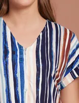 Blusa de seda fría a rayas verticales en tonos azul, marrón, blanco y celeste. Tiene escote en V y cierre frontal parcial con botones.