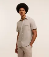 Camisa de hombre de manga corta en lino color blanco, con cuello clásico, botonadura frontal y bolsillo de parche en el pecho. Corte recto.