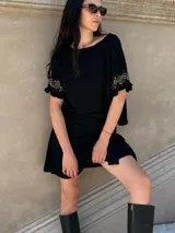 Remera negra de corte holgado con mangas cortas con volados y detalle de apliques de piedras en los volados.