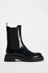 Botín Chelsea de cuero negro con elásticos laterales, tirador trasero y suela track con plataforma.
