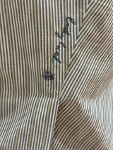 Remera a rayas verticales en tonos gris, blanco y ocre, con bordado en el frente.