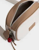 Bandolera de cuerina azul marino y beige con correa regulable azul y charm lateral decorativo. Tiene cierre superior y tag frontal con logo "The Brunch Club".