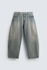 Pantalón de jean celeste con efecto lavado, corte holgado desde la cadera que se estrecha ligeramente en el bajo, tiro medio, cinco bolsillos y cierre frontal con cremallera y botón.