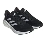 Championes de running Adidas Supernova 3, color negro con detalles en blanco. Presentan una parte superior de malla transpirable, acolchado en la lengüeta y el talón, mediasuela con amortiguación Bounce y Boost, y suela de goma.