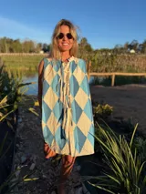 Vestido camisero corto con estampado de rombos en tonos beige, marrón y blanco. Tiene cuello camisero, cierre frontal con botones y corte holgado.