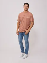 Remera color ladrillo de corte holgado, con estampa en la espalda con el logo de la marca y texto alusivo al surf.