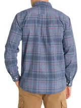 Camisa de franela de algodón orgánico a cuadros en tonos azul, gris y verde. Tiene cuello camisero, manga larga, un bolsillo en el pecho y cierre con botones.