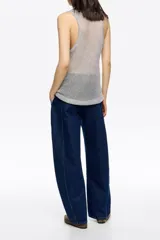 Pantalón de denim azul oscuro, corte barrel (tobillero con volumen en la cadera y estrechamiento hacia el tobillo). Presenta tiro medio, cierre frontal con corchete oculto y cremallera, y tiras ajustables con hebilla en la espalda.