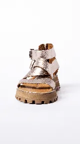 Sandalias de cuero color plateado con tiras anchas, hebillas metálicas y suela track color caramelo.