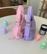 Cartera negra de lona semi impermeable con cierre metálico, forrería de gross y bolsillo interno. Tiene tira regulable y etiqueta blanca con texto en el frente.