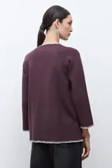 Saco de punto color ciruela oscuro, de manga larga y cuello redondo, con cierre frontal de botones y ribetes en contraste blanco con puntada decorativa.