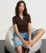 Blusa de punto acanalado (rib) color marrón oscuro, con cuello polo, escote en V y manga corta.