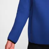 Campera deportiva Nike Tech Fleece color azul con cierre frontal, capucha y detalles en negro. Incluye logo de Nike bordado en el pecho y bolsillo con cierre en la manga izquierda.