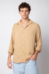 Camisa de manga larga color beige de lino, con cuello clásico y cierre frontal con botones.