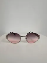 Lentes de sol con armazón metálico plateado y lentes redondos con degradé de negro a rosa.