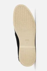 Mocasín casual de hombre color negro, con capellada de cuero serraje, corte liso con detalle de bordón y suela color crema.