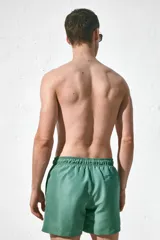 Short de baño verde con elástico y cordón ajustable en la cintura, bolsillos laterales y trasero con cierre autoadherente.