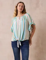 Blusa estampada de rayas verticales en tonos verde, celeste, amarillo y naranja, con cuello cuadrado, escote en V con aplique metálico y bordado con brillos. Tiene mangas cortas amplias y terminación con nudo en el ruedo.