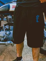 Bermuda negra oversize de gabardina de algodón con bordado azul en la pierna.