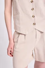 Chaleco corto color crudo de lino twill, con escote en V y cierre frontal con botones.