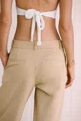 Pantalón color beige de tiro alto con bolsillos delanteros y falsos bolsillos de vivo en la espalda, de pierna ancha y corte recto. Cierre frontal con cremallera y botón.