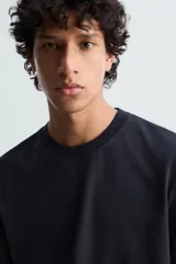 Camiseta blanca de algodón de peso medio, corte recto, cuello redondo y mangas cortas.