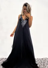 Vestido largo negro con escote en V y breteles finos. Presenta apliques de lentejuelas negras en el escote.