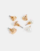 Set de tres pares de aros pasantes con forma de corazón: un par dorado con strass, un par blanco símil perla y un par dorado liso.