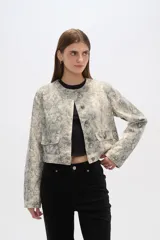 Chaqueta corta de algodón con estampado animal print en tonos grisáceos, cuello redondo, cierre frontal con botones a presión, bolsillos de parche en el pecho y corte recto.