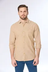 Camisa de lino color beige, de manga larga, con cuello clásico y bolsillo en el pecho.
