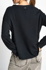 Sweater negro de algodón peinado con elastano, corte oversize y mangas largas con rayas blancas en los brazos.