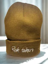 Gorro de lana sintética color marrón con bordado frontal de la frase "Risk takers".
