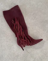 Bota alta de cuero color borgoña con taco fino y detalle de flecos en el lateral.