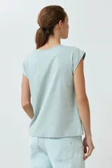 Remera de manga corta color verde agua con bordado floral blanco en la zona del pecho y cuello con abertura en forma de lágrima.