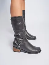 Bota de caña media color negro, de cuero vacuno, con taco de madera y detalle de arnés con aro metálico plateado.