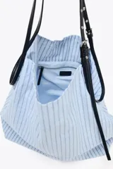 Bolso tipo shopper en tejido con rayas celestes y grises. Asa a contraste de color negro y material sintético con detalles metálicos.