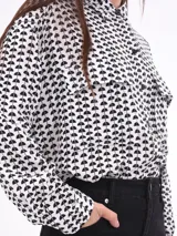 Camisa blanca estampada con motivos geométricos negros, de corte holgado, manga larga y cuello camisero.