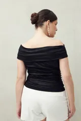 Top negro con escote off-shoulder, confeccionado en tejido de punto con efecto satinado y corte ajustado.