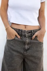 Jean de mujer color gris con efecto acid wash, de corte recto y tiro alto. Incluye bolsillos traseros y etiqueta de marca blanca en la cintura.