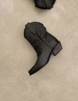 Botas cortas negras de cuero con bordados blancos estilo cowboy.