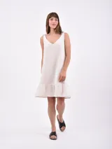 Vestido corto color crudo, de lino, con breteles finos con lazos y volado en el ruedo.