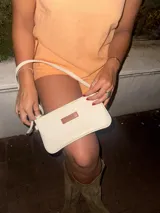 Cartera de mano tipo clutch, color marrón, confeccionada en cuero.