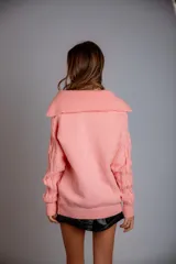 Buzo de punto color crema con cierre metálico y cuello alto.